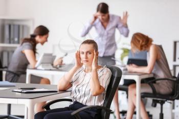 Stressed woman with headache and noisy people in office�