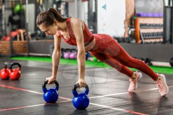 Sporty young woman training with kettlebells in gym�