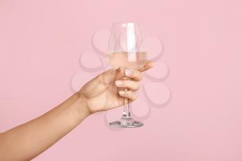 Hand with glass of wine on color background�