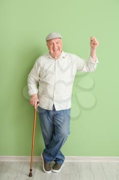 Senior man with walking stick near color wall�