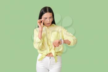 Stressed young woman with watch on color background�