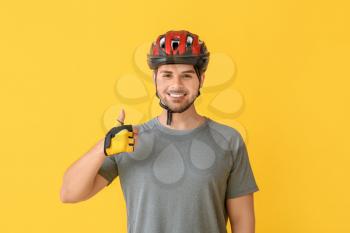Male cyclist showing thumb-up on color background�