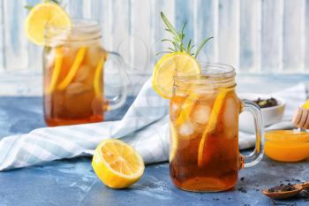 Mason jars of cold black tea with lemon on color background�