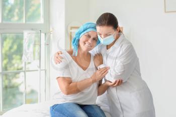 Doctor comforting mature woman after chemotherapy in clinic�