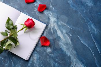 Book with blank pages and beautiful red rose on color background�