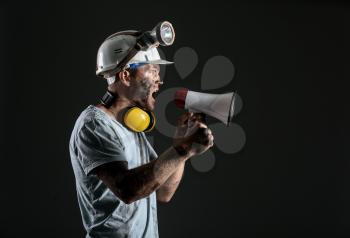 Protesting miner man with megaphone on dark background�