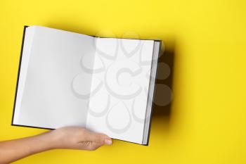 Woman holding open book on color background, closeup�
