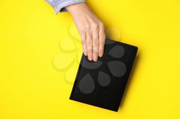 Woman holding book on color background�