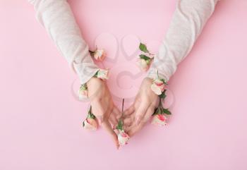 Female hands with beautiful flowers on color background�