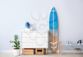 Interior of modern stylish hall with surfboard, shoe stand and chest of drawers 