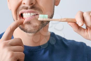 Man with aching teeth and brush on grey background�