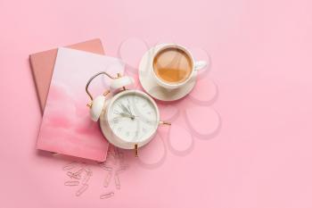 Composition with alarm clock and cup of coffee on color background�