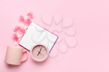 Composition with alarm clock, cup and notebook on color background�