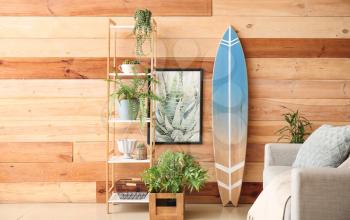 Interior of modern stylish room with sofa, shelf unit and surfboard�