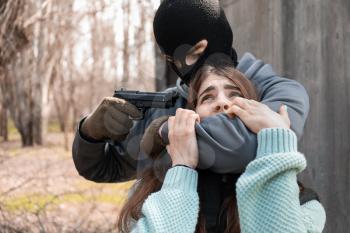 Terrorist aiming at female hostage outdoors�