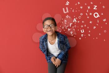 Laughing African-American little boy and letters coming out of his mouth on color background�
