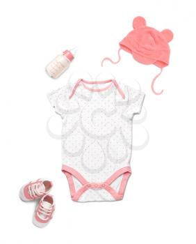 Baby clothes with booties and bottle of milk on white background�