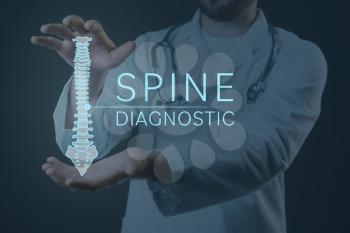 Male doctor with holographic projection of human spine on dark background. Innovative technologies in medicine�