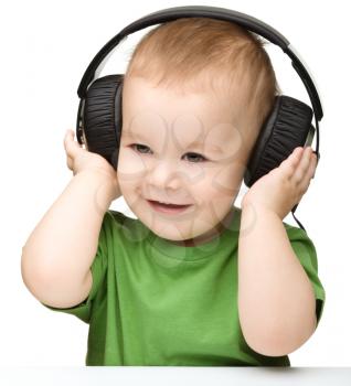 Cute little boy enjoying music using headphones, isolated over white