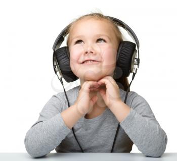 Cute little girl enjoying music using headphones, isolated over white