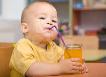 Cute boy is drinking orange juice using straw