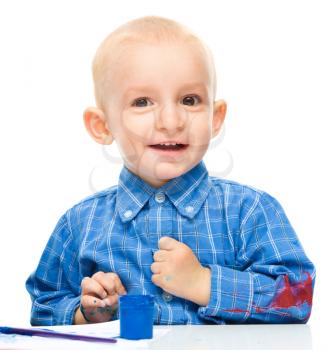 Portrait of a cute little boy playing with paints, isolated over white