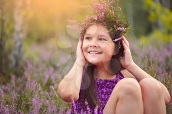 Girl is holding wreath of heather flowers, outdoor shoot