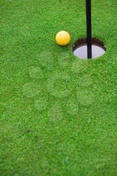 Golf ball on the edge of hole on the green grass