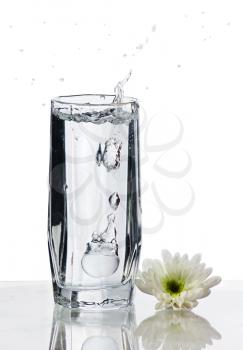 Glass of Water with splash and flower on isolated white background