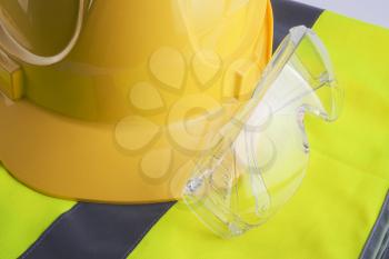 Yellow vest and helmet with protection glasses close up