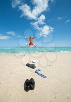 young businessman jumping on the beach after a big deal