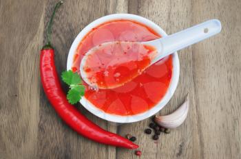 red hot chilli sauce over wooden background