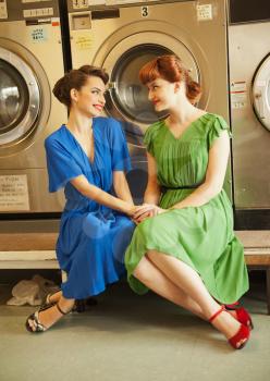 young sisters in retro style sitting together in laundry