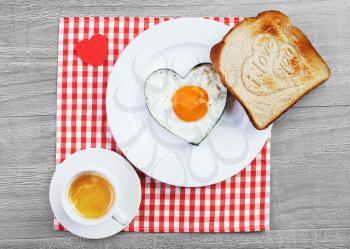 Fried egg  in heart shape  and toast with love message.Breakfast for a loved one