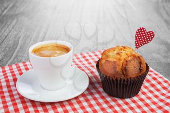 Coffee cup and muffin on grunge wooden background