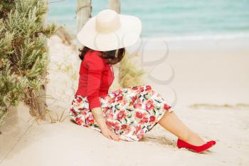 Beautiful lady in red  sitting near the sea in retro style.Local focus on the woman