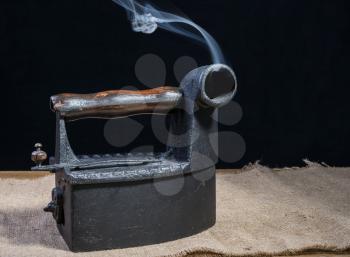Hot Retro charcoal iron with smoke on wooden table