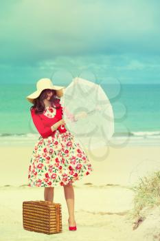 beautiful lady in red with umbrella near the sea in retro style 