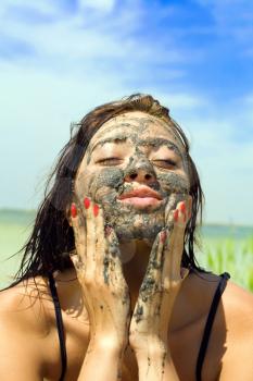 Royalty Free Photo of a Young Woman Rubbing Mud on Her Face