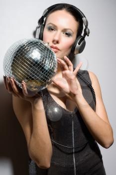Portrait of attractive young brunette in headphones with a mirror ball