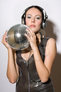 Portrait of pretty young woman in headphones with a mirror ball