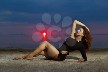 Attractive young woman lying on the shore at sunset