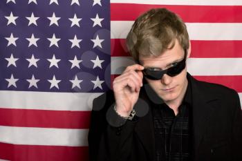 Serious man in sunglasses on a background of the American flag