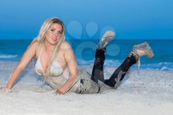 Sexy blond woman in wet clothes posing on the beach