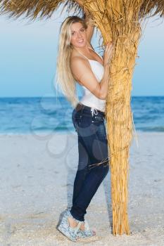 Smiling young blonde posing in casual clothes near a palm