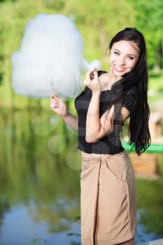 Pretty smiling woman posing with a cotton candy near the pond
