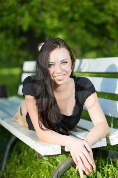 Young smiling brunette lying on the bench