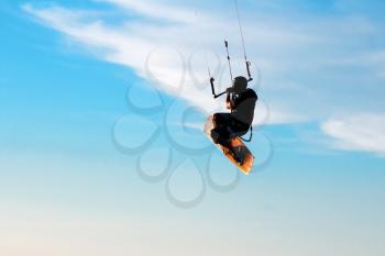 Silhouette of a kitesurfer flying in the blue sky