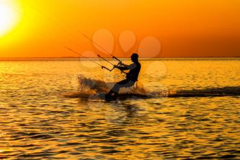 Silhouette of a kitesurfer sailing in the gulf at sunset