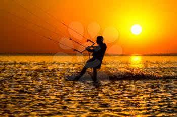 Silhouette of a kitesurfer sailing in the evening